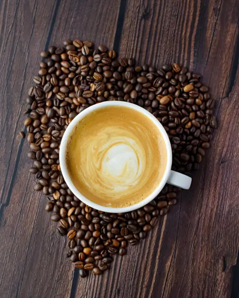 Cappuccino with latte art on a bed of coffee beans